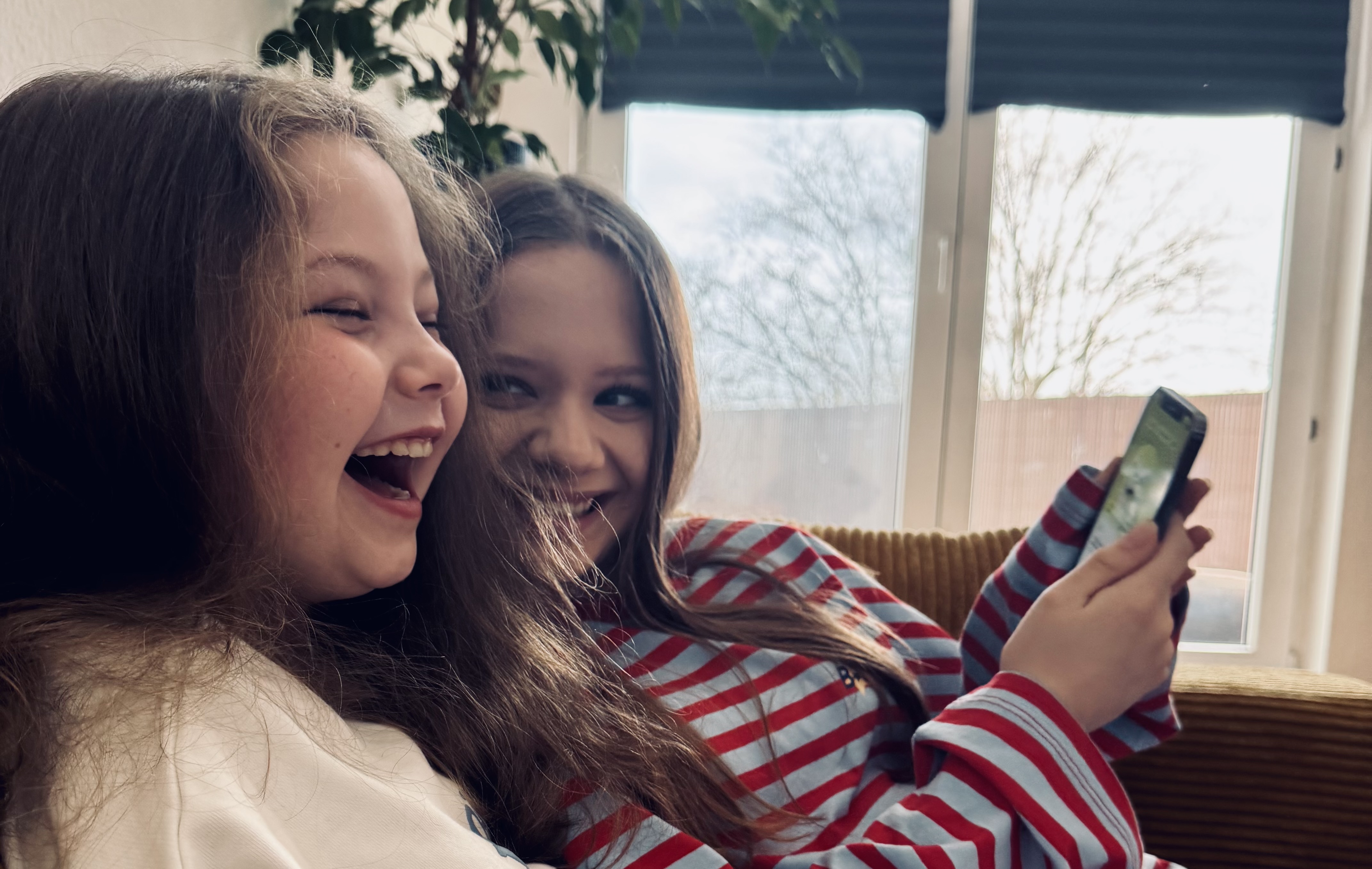 Sofiia and Elli laughing together on the couch while using Erny